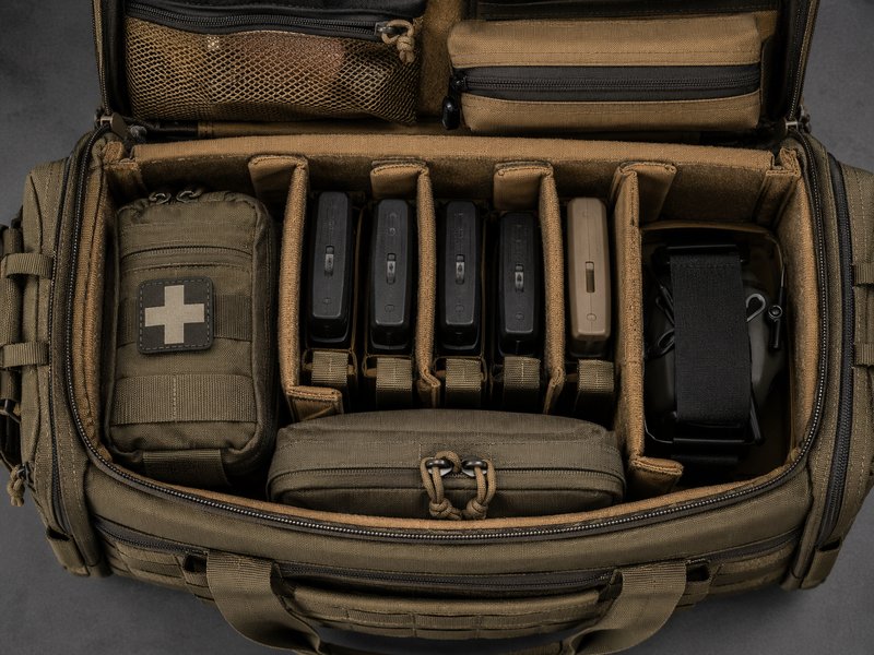 Overhead view into an organized tactical range bag showing compartments and pouches